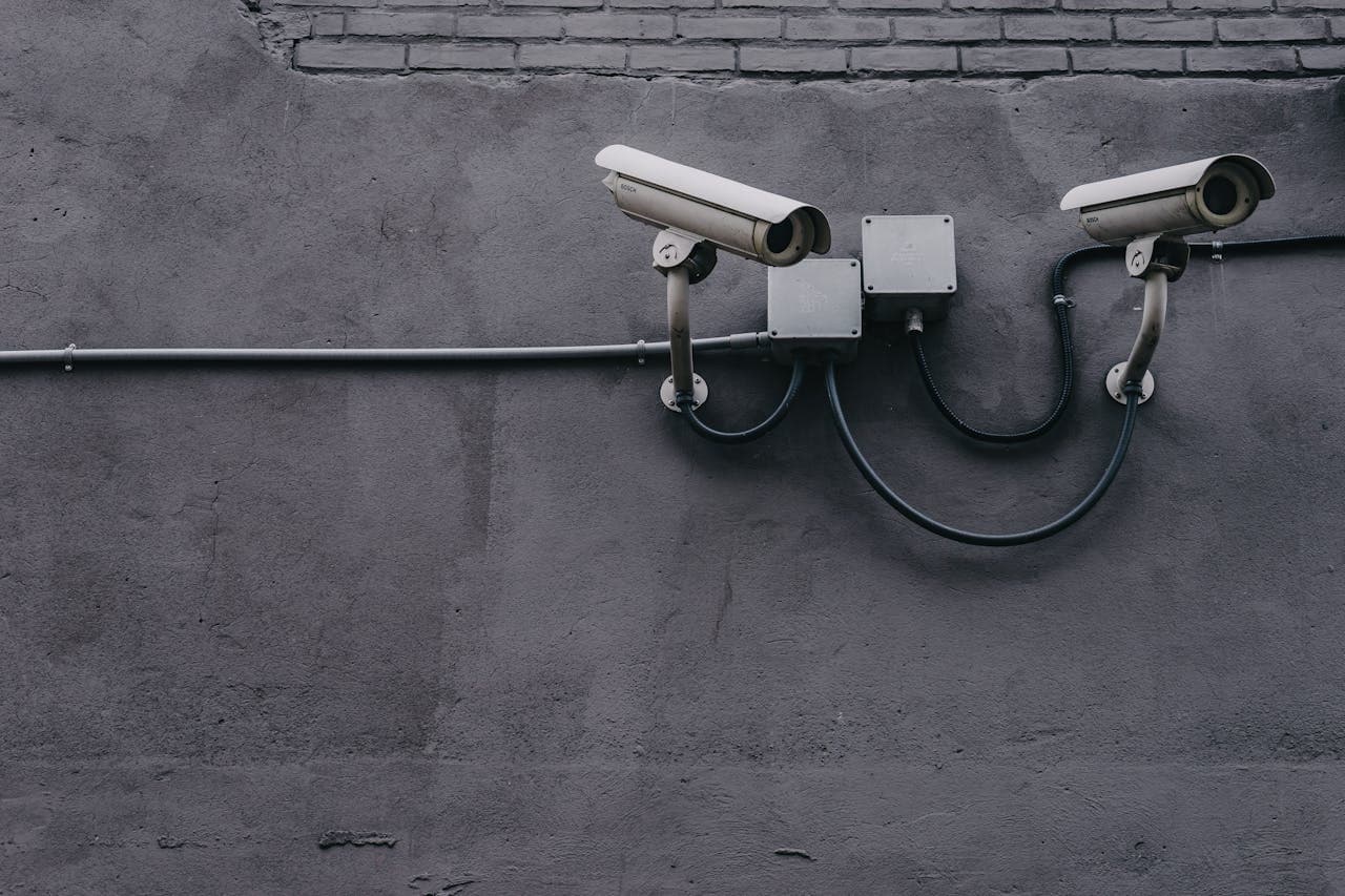 Two large CCTV cameras on a grey commercial building